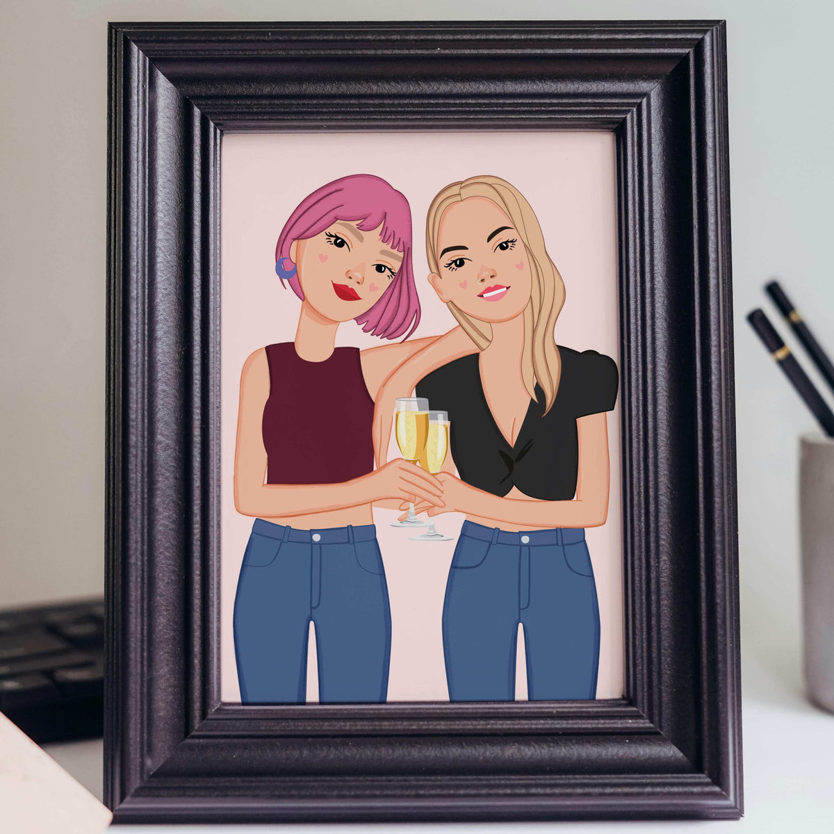 Personalized bestie caricature portrait with personalized hair colors and outfits, shown as a framed office desk accessory for a meaningful 20th or 30th birthday gift. Artwork by Costanza Tonini Design