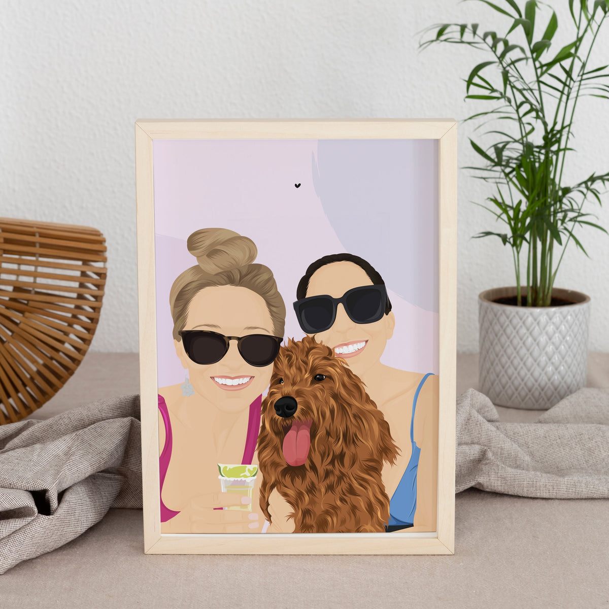 Custom digital illustration of two women smiling with their brown golden doodle dog. The portrait is framed in a light wood frame, creating the perfect gift for a family with a pet or a unique housewarming keepsake.