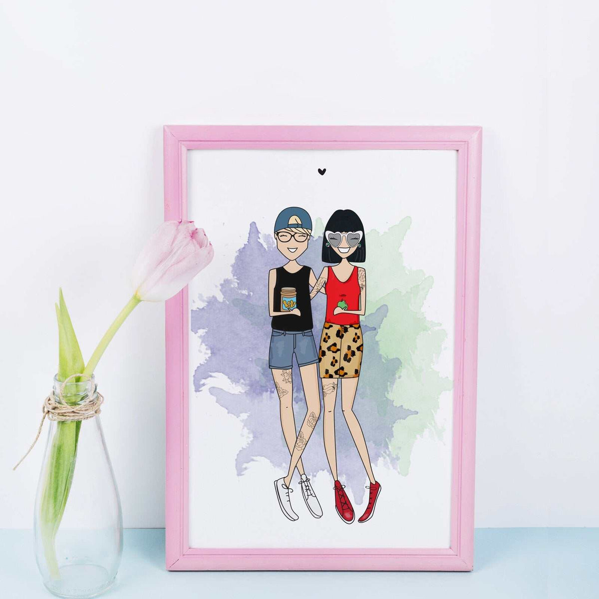 A framed illustration of two people standing side-by-side. The person on the left is wearing a blue baseball cap, a black shirt, blue denim shorts, and white trainers. The person on the right is wearing a red tank top, a leopard print skirt, and red trainers. The background is a watercolour wash of purple, blue, and green. A trendy, custom birthday gift for a quirky best friend or a fun fashion-focused roommate present.