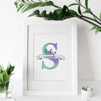 A hand-drawn Mother’s Day card featuring a large turquoise floral initial "S" decorated with lavender and green leaves. A white banner across the letter displays the name "Sarah" in elegant script. At the bottom, a heartfelt Mother's Day quote. This personalized A5 thank you gift has a clean, artistic feel, perfect for a sentimental keepsake.