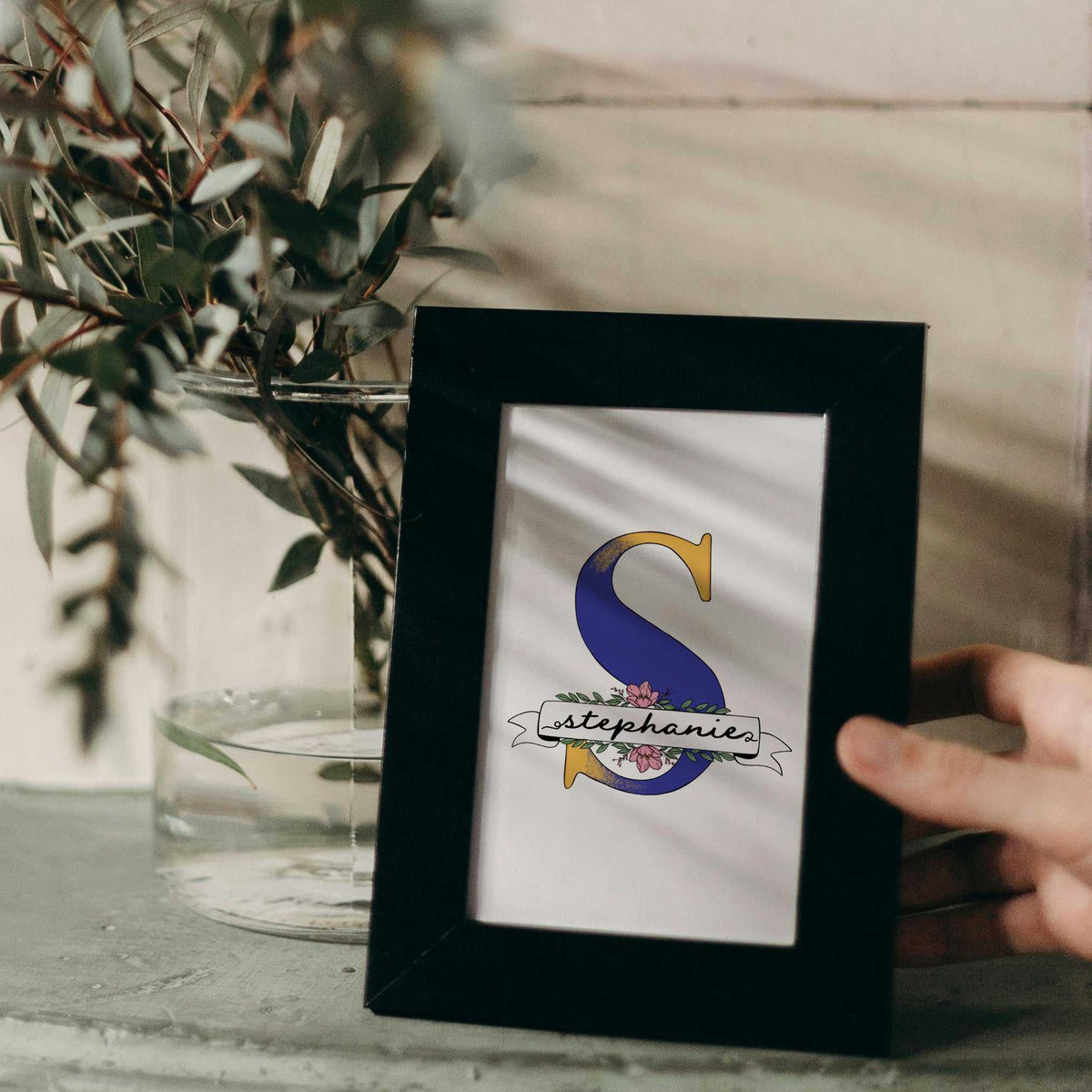 A hand-drawn Mother’s Day card featuring a large blue floral initial "S" decorated with pink blossom and green leaves. A white banner across the letter displays the name "Stephanie" in elegant script. At the bottom, a heartfelt Mother's Day quote. This personalized A5 thank you gift has a clean, artistic feel, perfect for a sentimental keepsake.