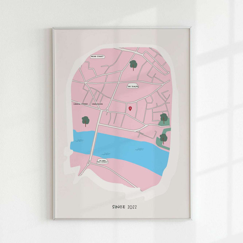 A minimalist personalized map art print of London in pink and blue, featuring a red location pin near The Scalpel and Cannon Street. The custom map includes hand-drawn street details, a river, and 'Since 2022' text at the bottom. Framed against a white wall with soft shadows.