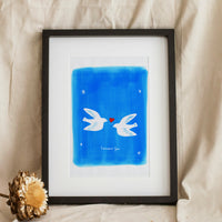 A vertical hand-painted illustration on textured white paper featuring two white doves flying toward each other over a small red heart. The background is a vibrant, hand-brushed cerulean blue with small white stars in the corners and the romantic French script "l'amour fou" centered at the bottom.