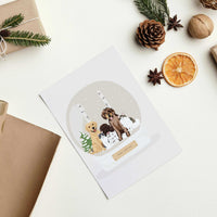 Festive holiday flat lay featuring a multi-pet design on a Personalized Pet Portrait for Christmas Card with four custom hand-drawn dogs and cats inside a snow globe.