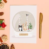 Custom hand-drawn illustration of a chihuahua and playful ginger cat with holiday lights on a Personalized Pet Portrait for Christmas Card next to a gold pen.