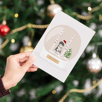 Hand holding a custom holiday card featuring a Personalized Pet Portrait for Christmas Card with a hand-drawn gray tabby cat wearing a festive Santa hat.