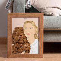 A personalized pet and owner portrait illustration of a blonde woman and her fluffy brown Labradoodle dog, propped against a living room sofa in a rich wood frame as a warm housewarming gift.